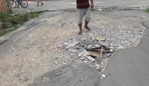Moradores precisam tapar buracos com cascalhos para amenizar a situação da rua Edson, no bairro Novo Aleixo