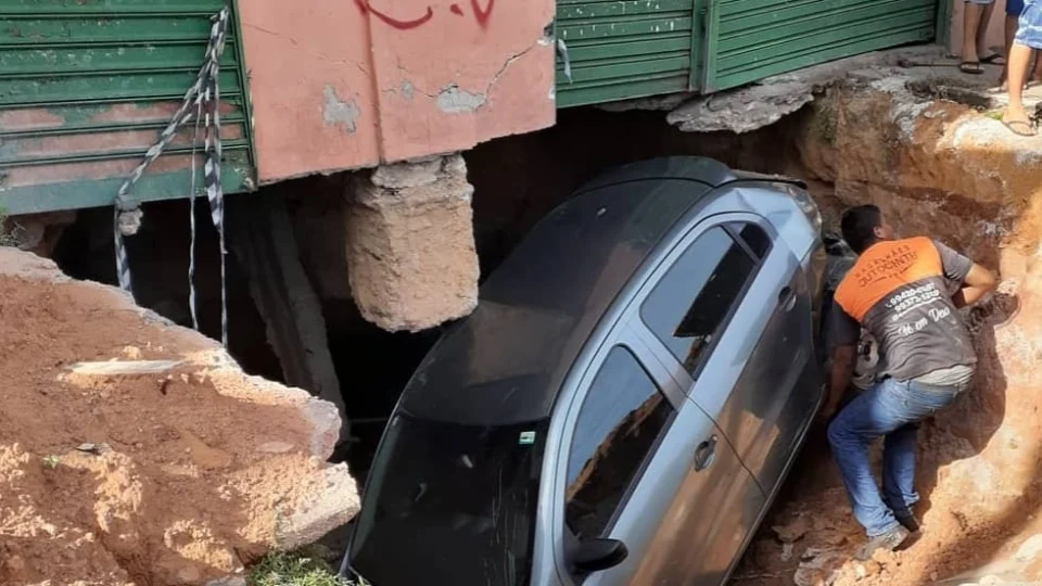 Motorista dorme ao volante e colide com carro estacionado na via e este cai em cratera gigantesca