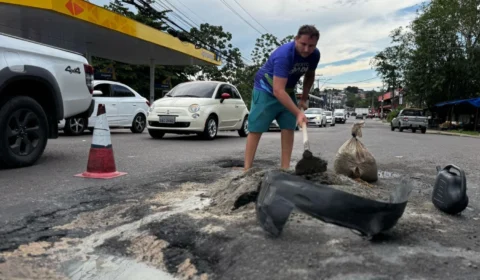 Moradores realizam tapa-buracos por conta própria na avenida Sumaúma, na Cidade Nova, zona Norte de Manaus