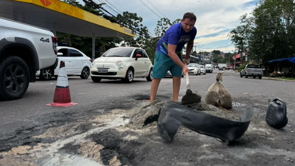 Moradores realizam tapa-buracos por conta própria na avenida Sumaúma, na Cidade Nova, zona Norte de Manaus